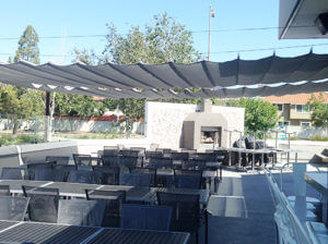 Image of horizontal shade sail covering patio at restaurant with fireplace.